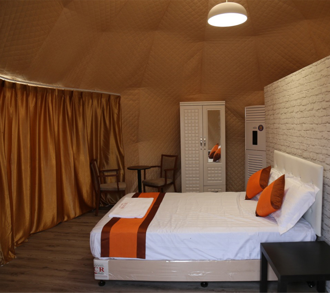 Cozy interior of a premium dome tent with a bed, wardrobe, and seating area.
